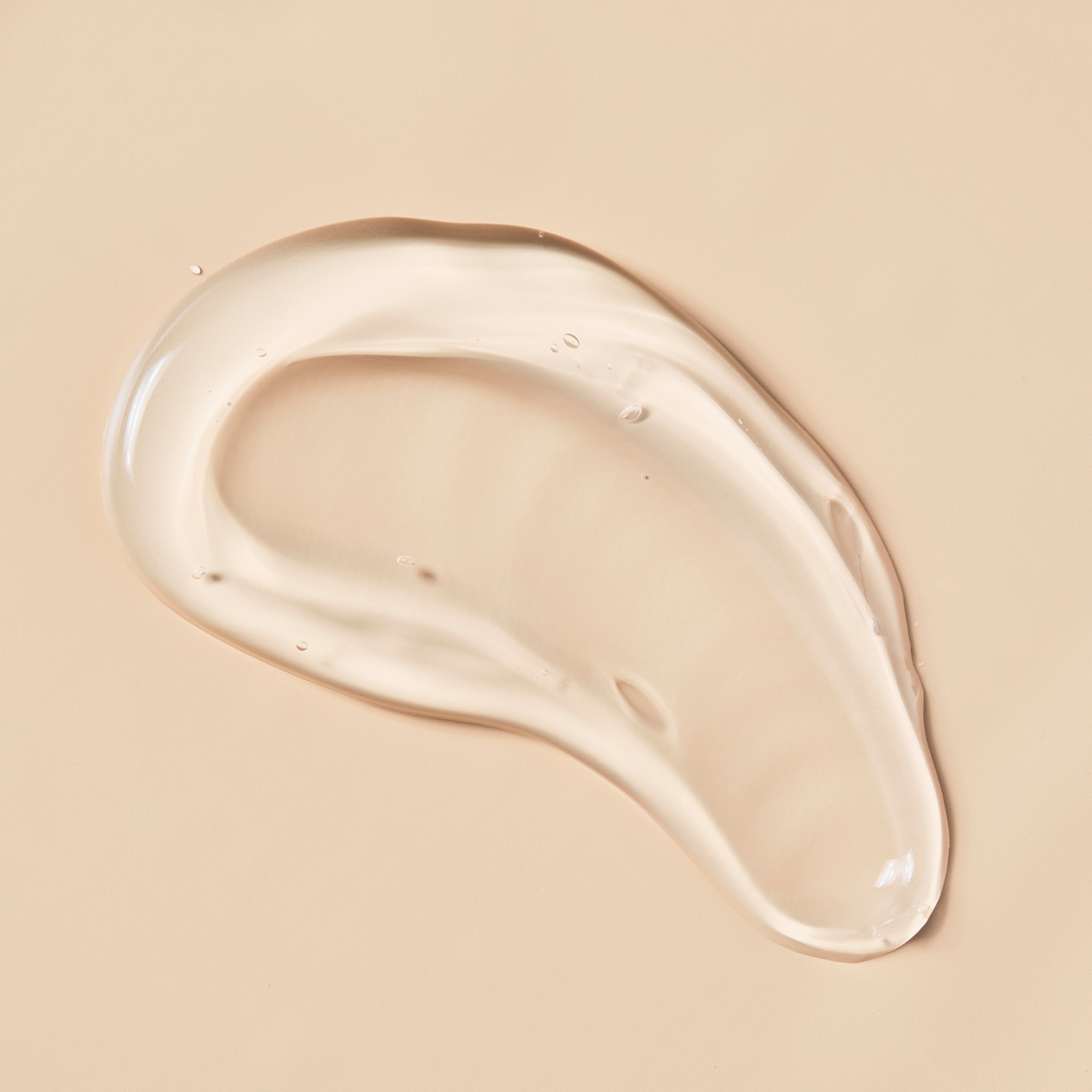 Clear aloe vera gel swatch spread on soft beige background showing smooth glossy texture