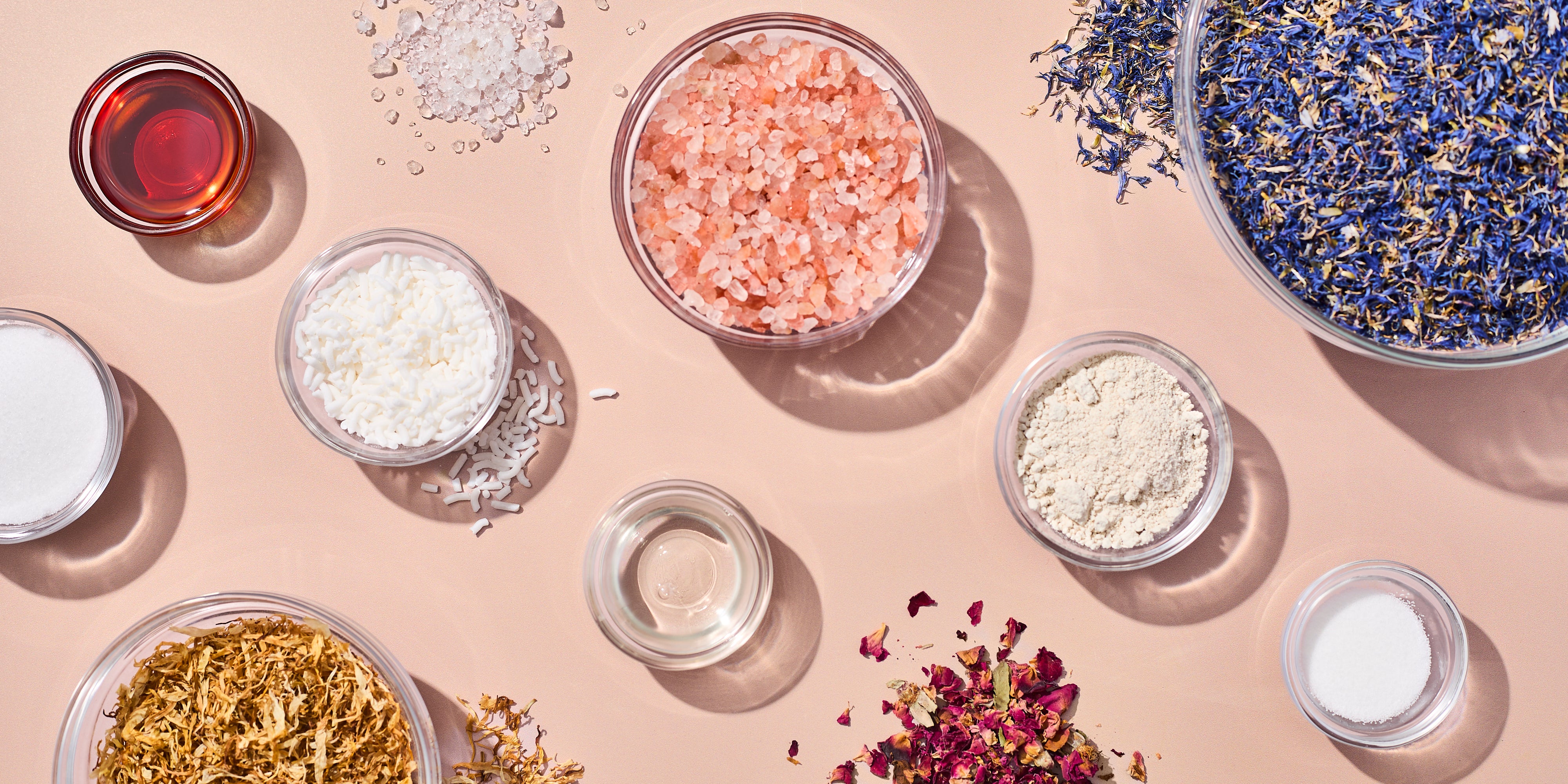 Assorted additives in small bowls on a peach surface shot top down