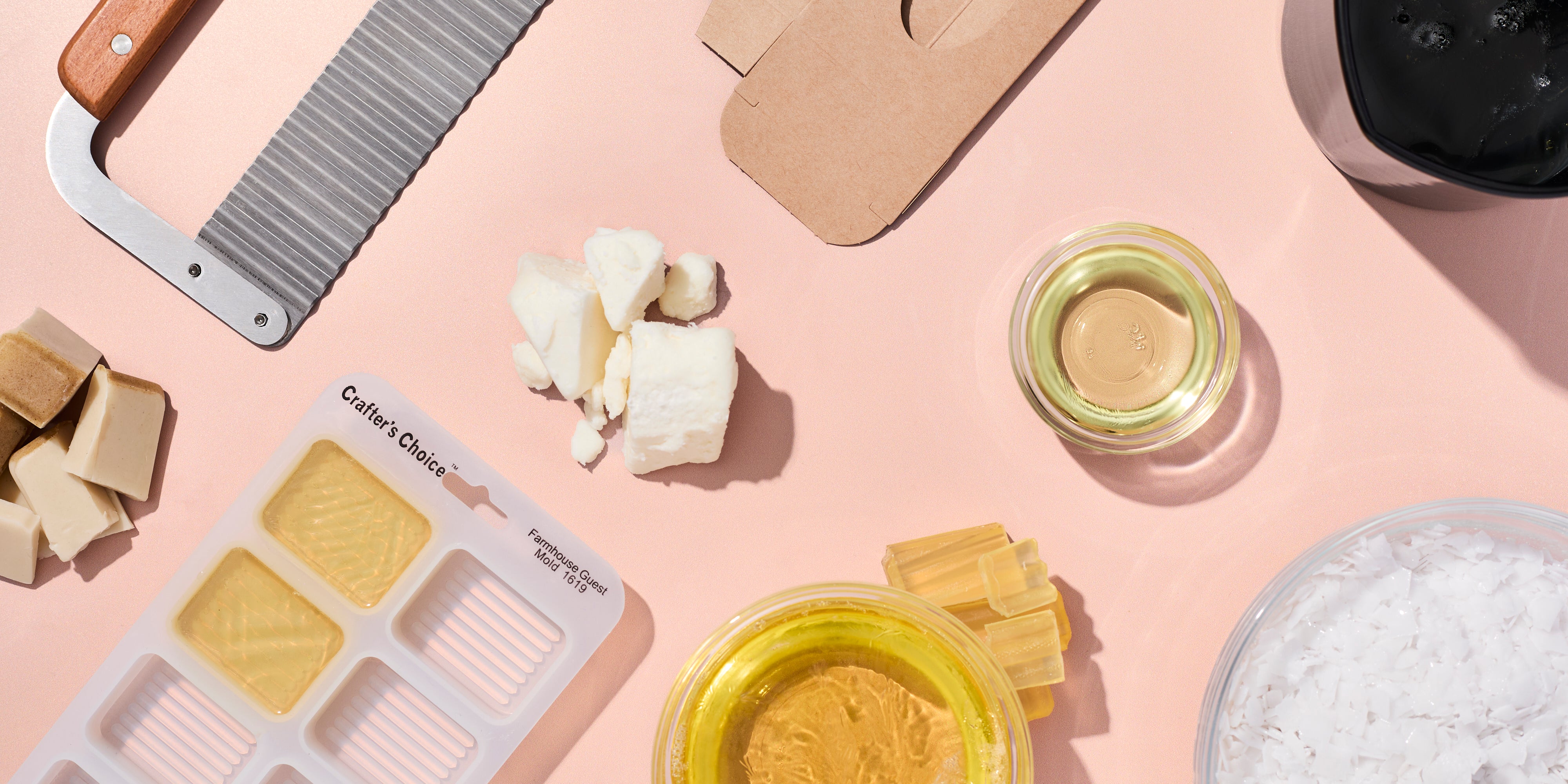 Assorted beauty products including a palette, cream, and jars on a pink background