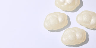 Four pearlescent cloud-shaped soap bars arranged on a clean white background with soft shadows and ample negative space.