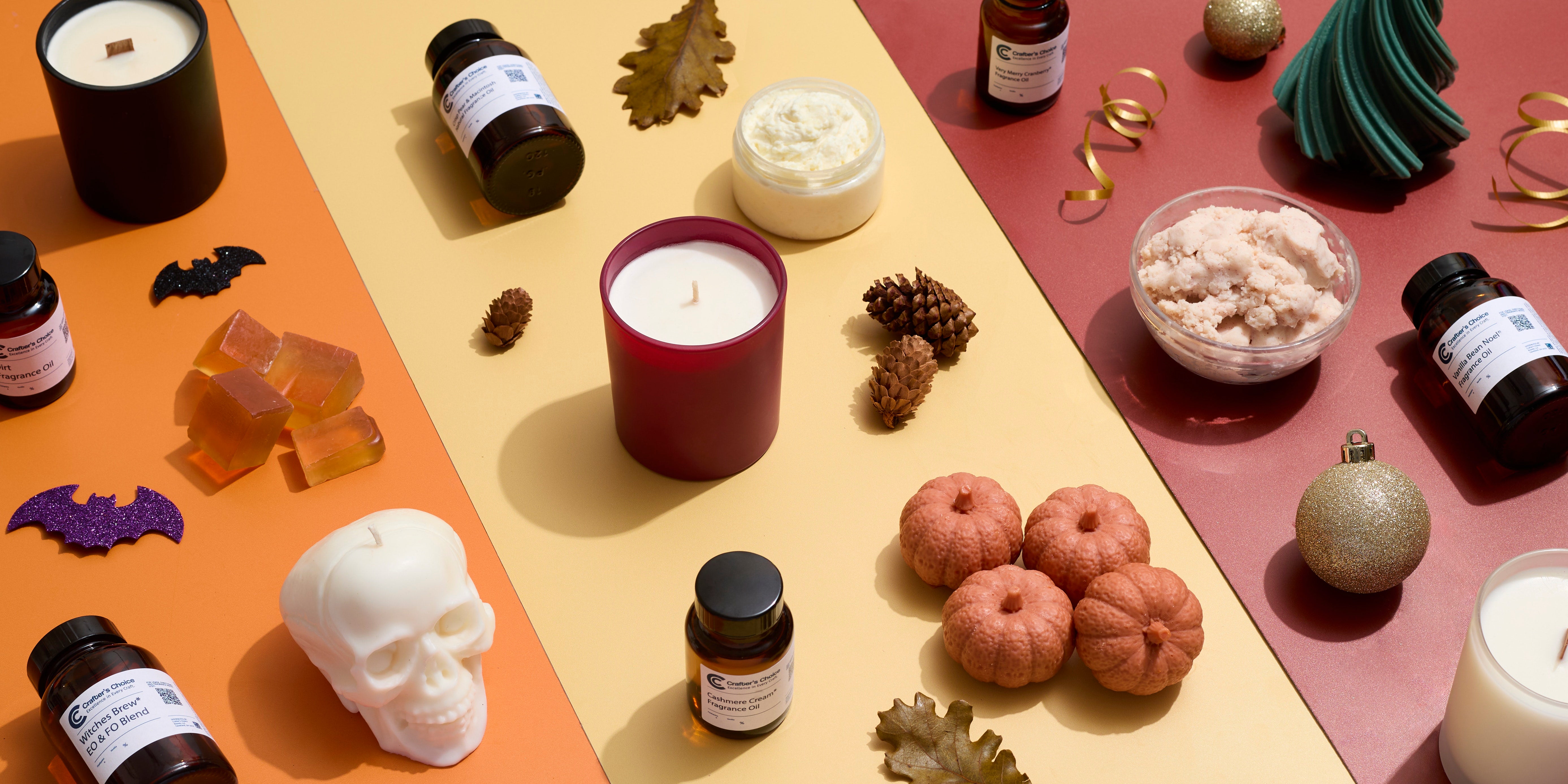 Seasonal candles, fragrance oils, soaps, and body scrubs arranged on orange, yellow, and red backgrounds with Halloween skulls and bats, autumn pumpkins and leaves, and a green Christmas tree candle.
